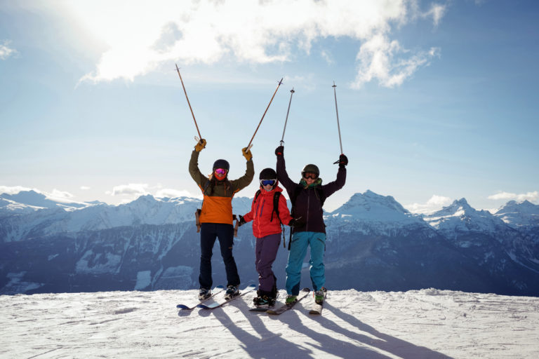 Celebrating skiers standing on snow covered mountain during winter