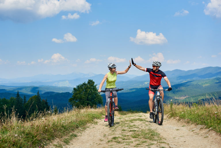 Happy couple bicyclists in professional sportswear and helmets riding cross country bicycles
